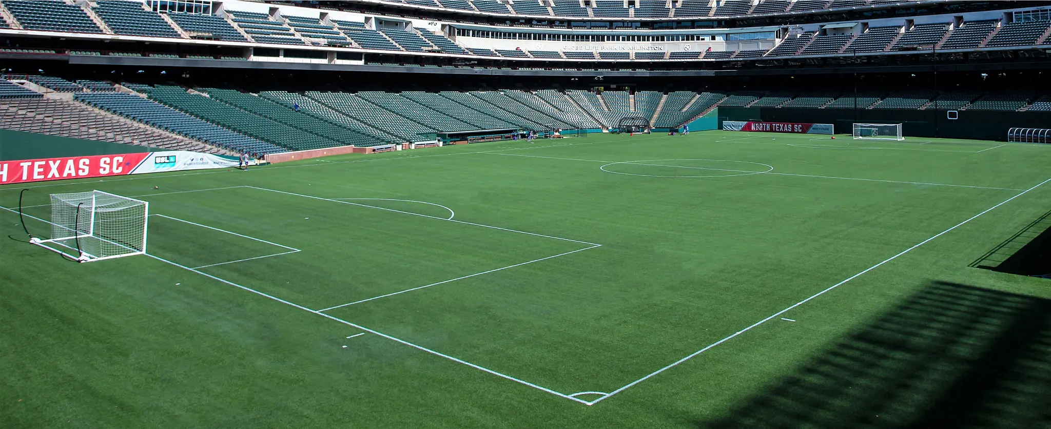 Artificial turf soccer field in a large stadium with empty seats