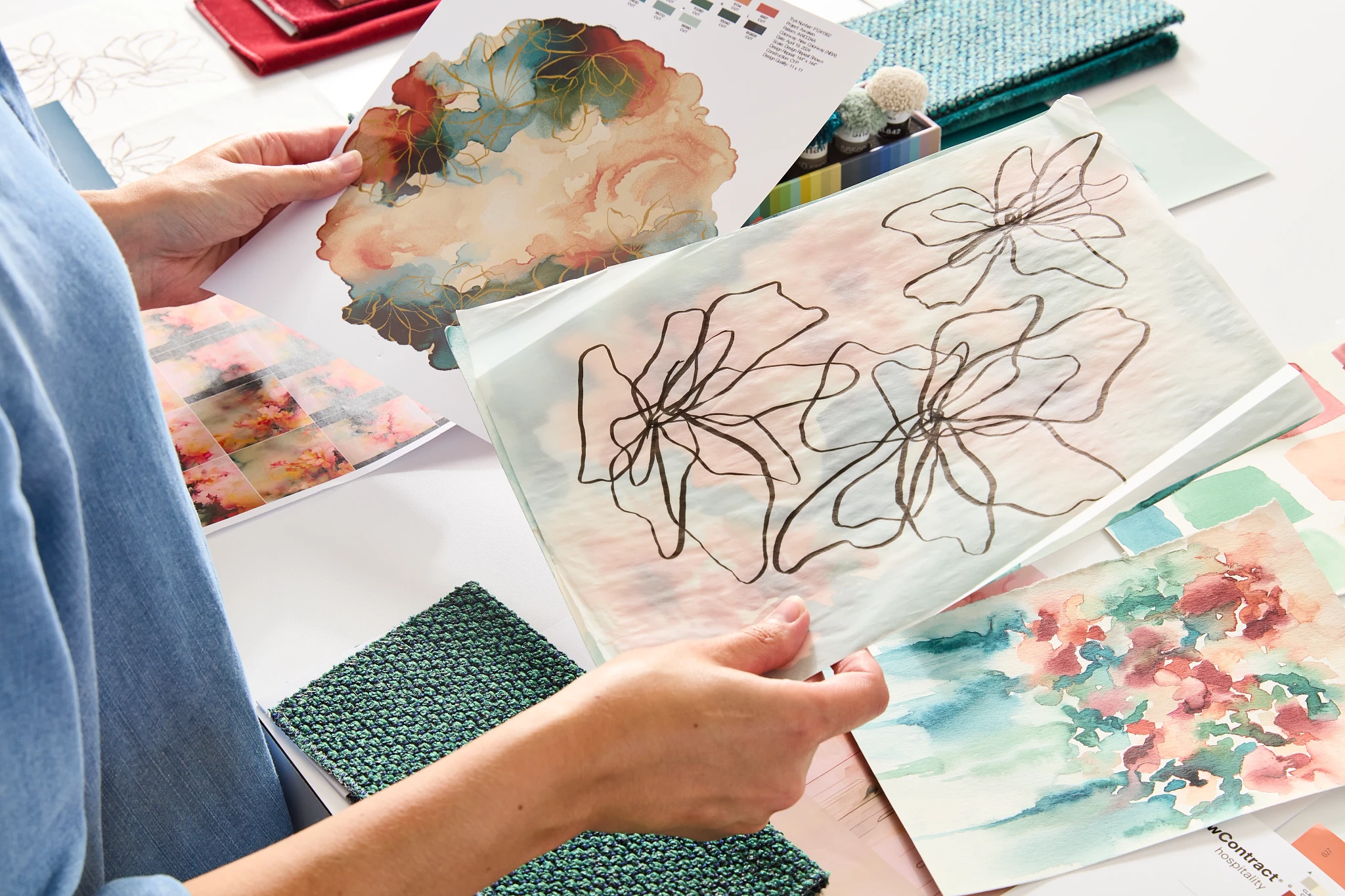 Designer reviewing colorful fabric swatches and abstract art prints