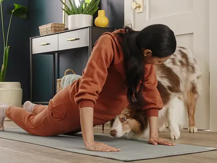 Modern Living Room with Wood Look Luxury Vinyl Plank Flooring Woman doing yoga with a dog on wood look luxury vinyl plank flooring in a modern living room