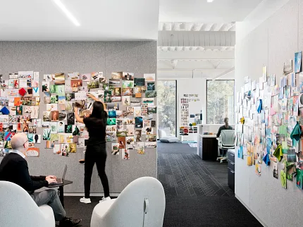 Contemporary office with dark carpet flooring and collaborative workspace design Modern office space with two people collaborating, featuring dark carpet flooring and creative wall displays