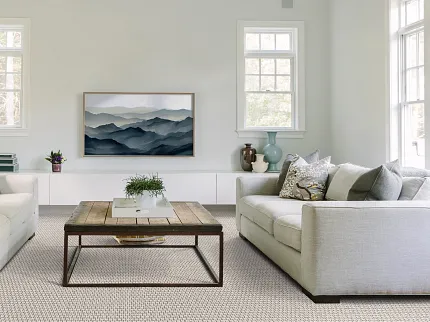 Modern Living Room with Beige and Gray Patterned Carpet - Shaw Floors Soft Surface Modern living room with soft surface flooring, featuring a beige and gray patterned carpet, two light gray sofas, a wooden coffee table, and a landscape painting on the wall