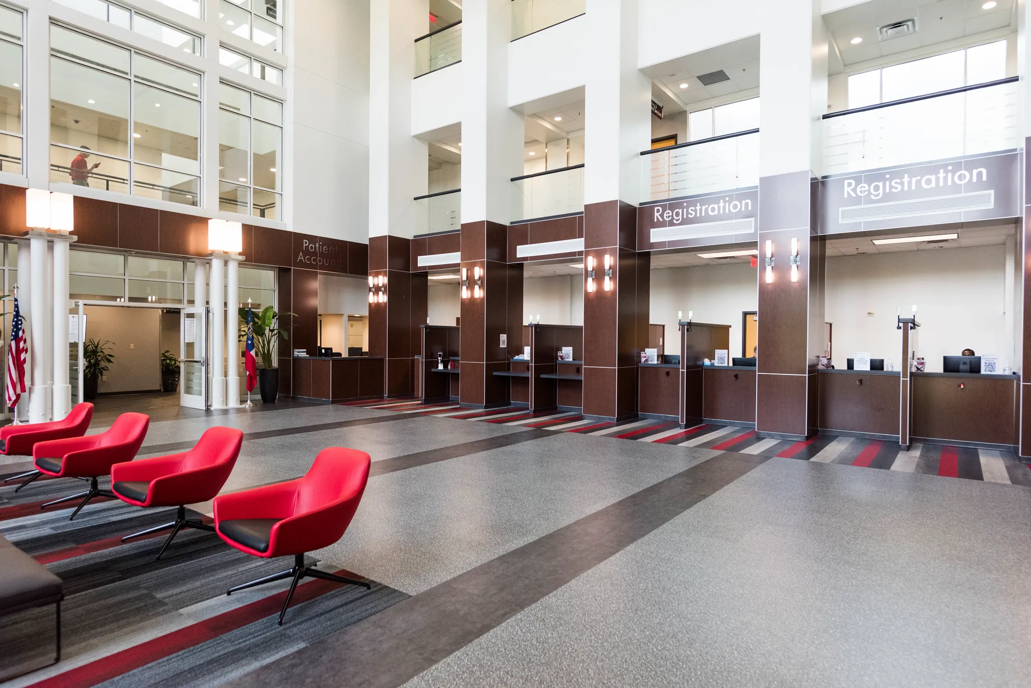 Modern healthcare facility lobby with red chairs and commercial carpet tile flooring in shades of gray and red