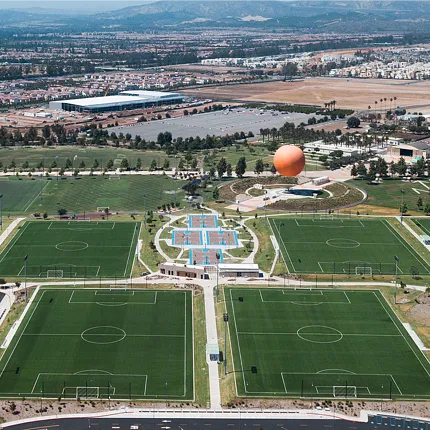 Soccer fields with artificial grass in a park setting Aerial view of multiple soccer fields with artificial turf surrounded by a park and residential area