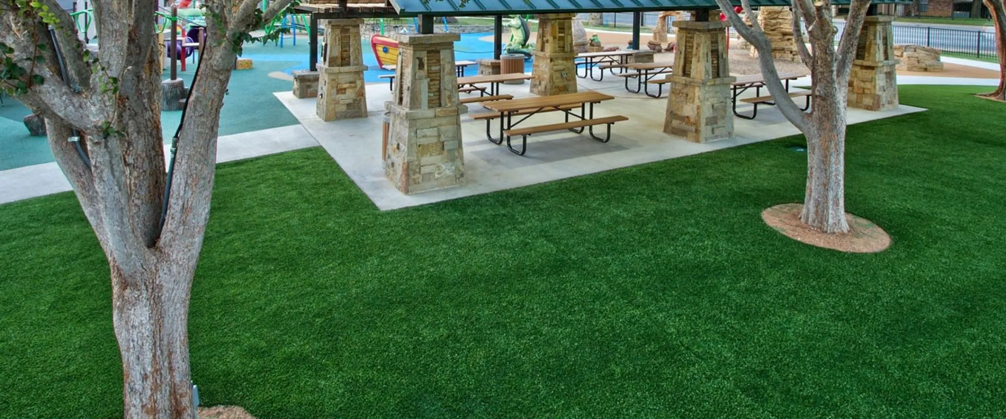 Outdoor park scene with artificial grass and picnic tables