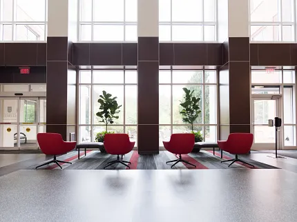 Education Facility Lobby with Modern Flooring and Red Chairs Modern education facility lobby with red chairs and large windows, featuring sleek flooring design