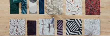 Carpet Tile Swatches Display on Wooden Floor Overhead view of diverse carpet tile swatches in various colors and patterns on a wooden floor with two people arranging them