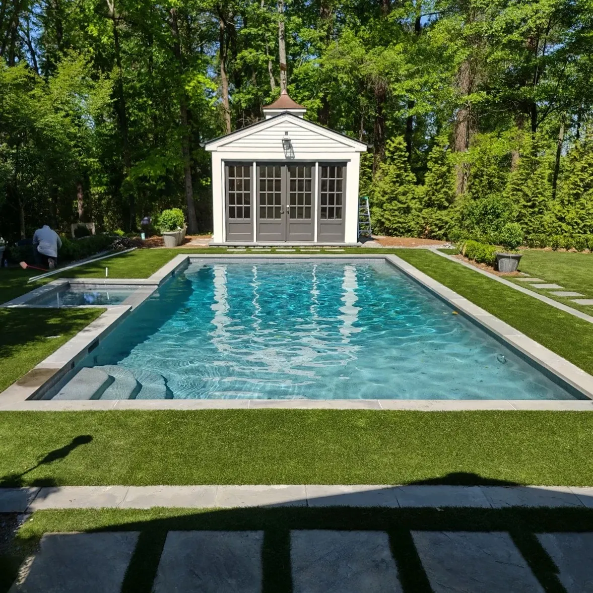 Outdoor pool with surrounding greenery and pool house