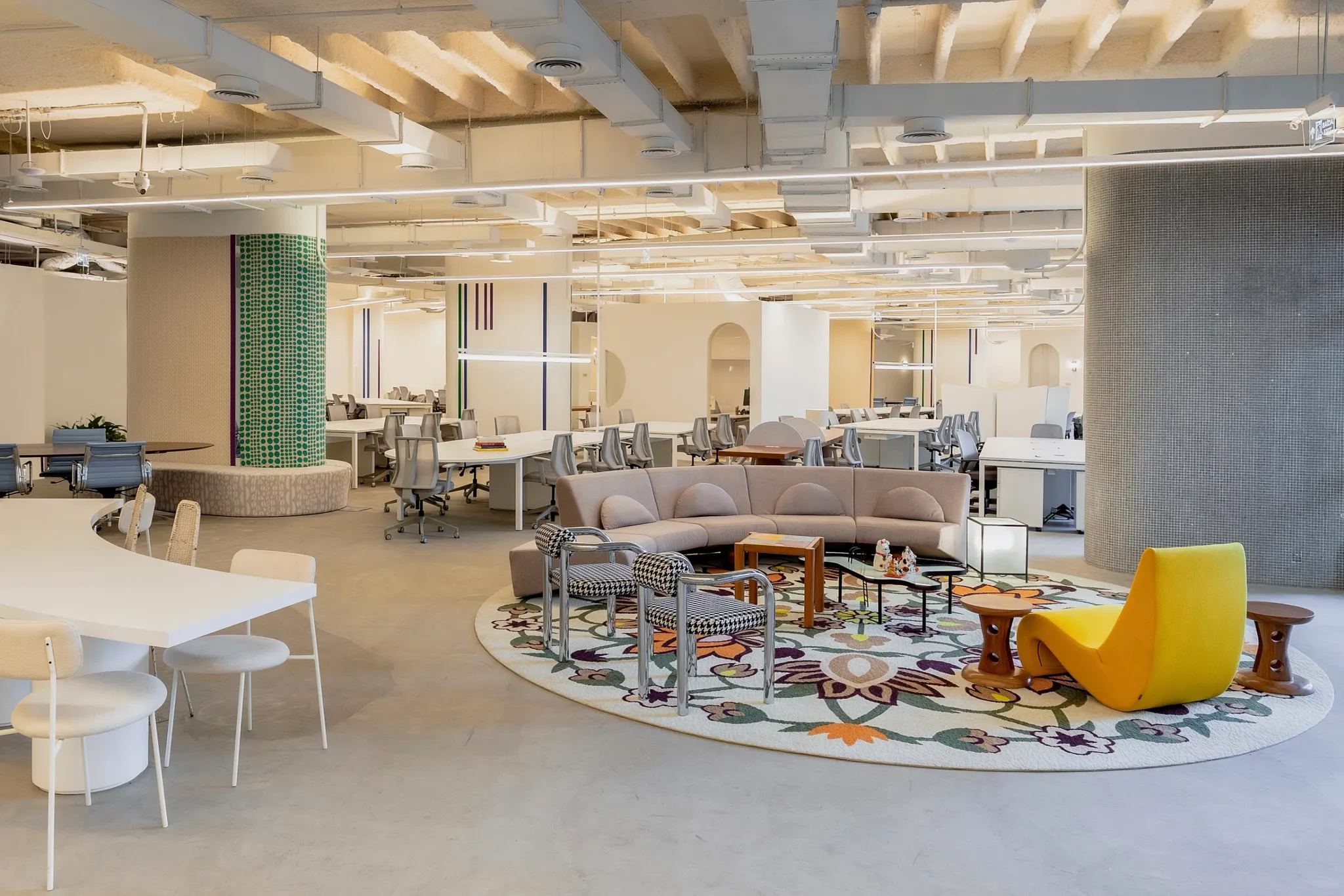 Espacio de oficina moderno con piso de concreto y área de descanso colorida