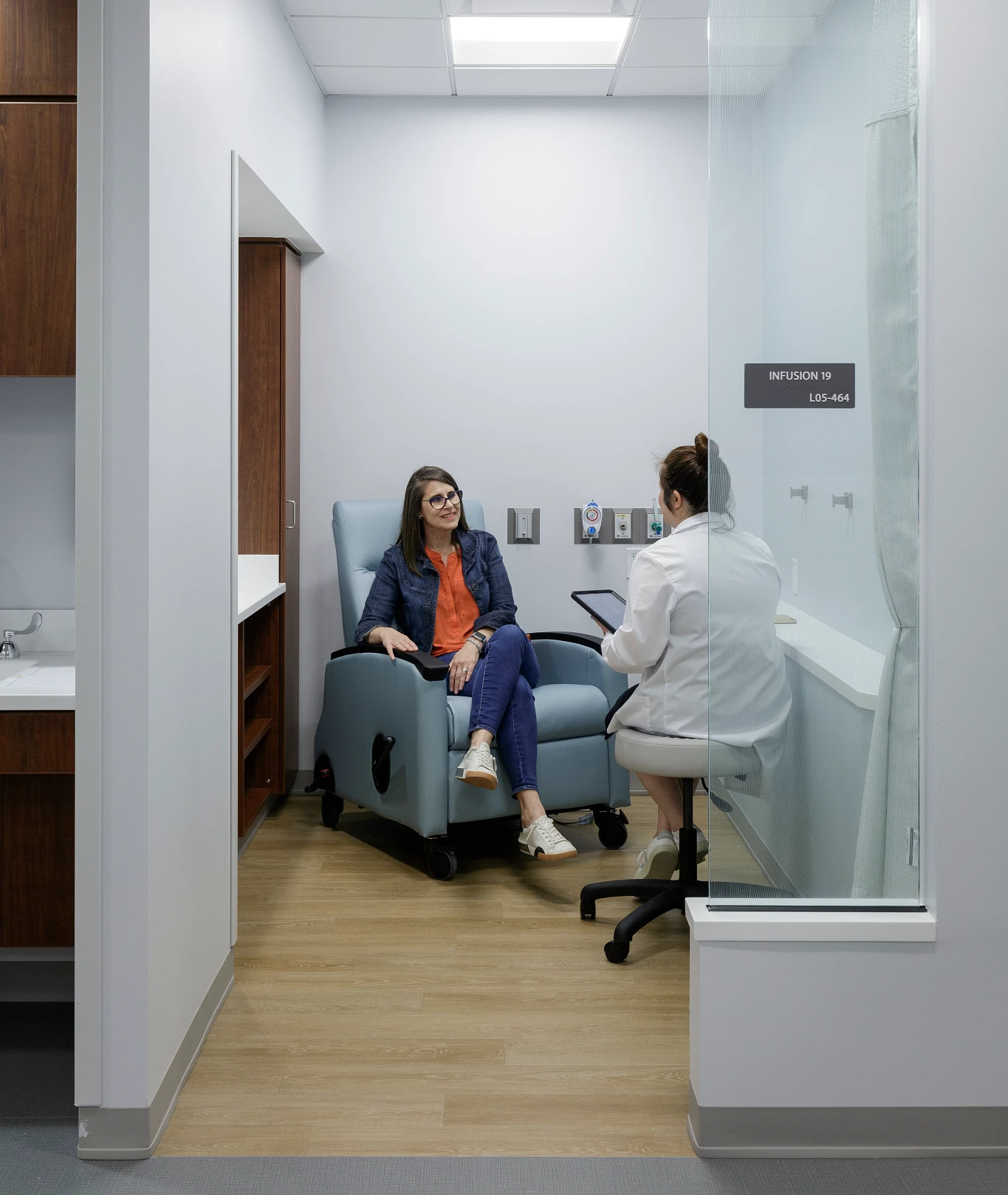 A doctor sitting with her patient in a Infusion room at the medical center