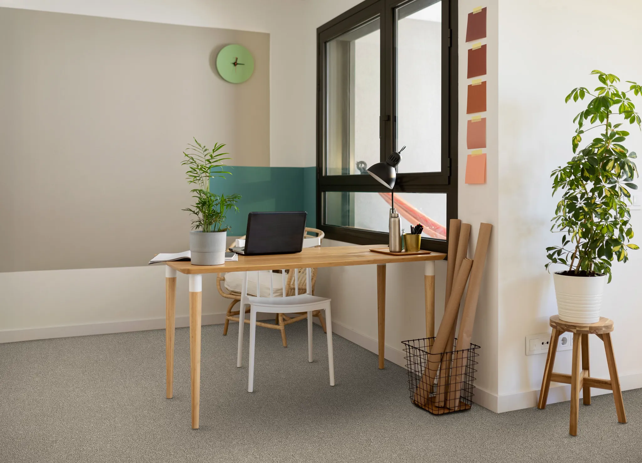 Modern home office with light gray carpet flooring, wooden desk, and potted plants