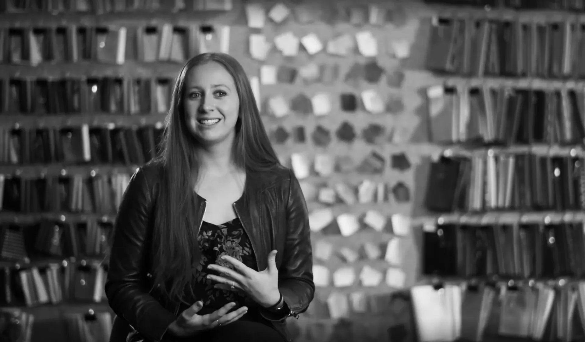 Woman in a leather jacket sitting in front of a wall of flooring samples
