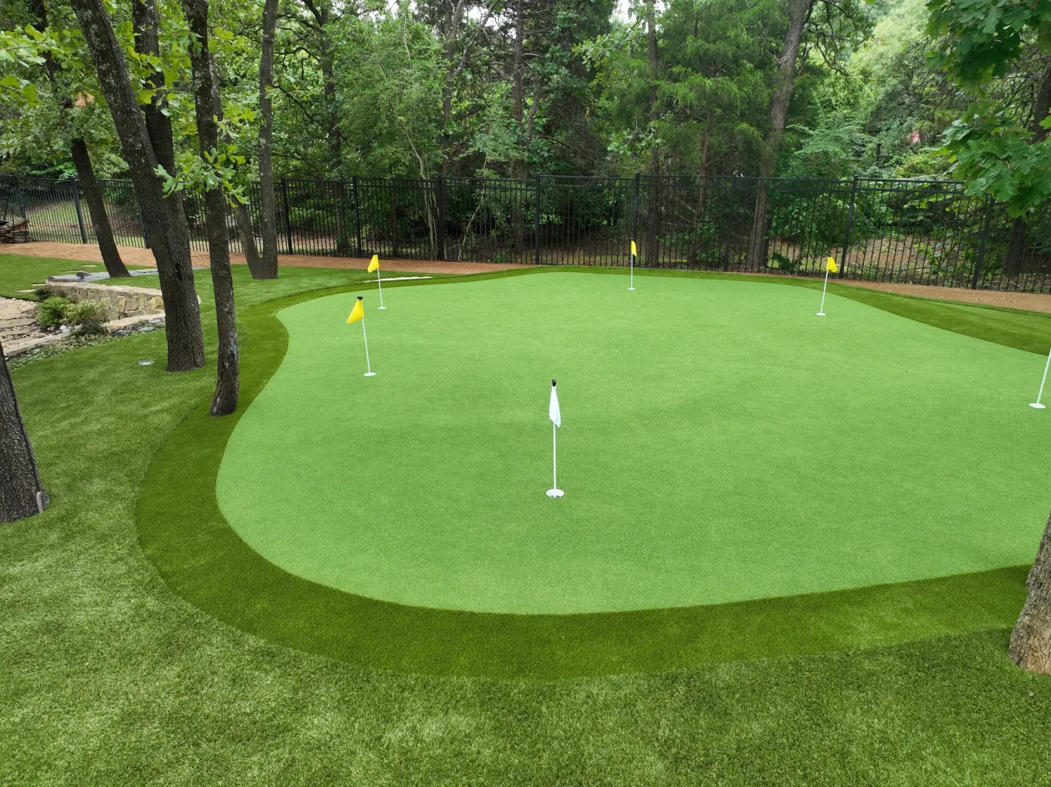 Artificial grass putting green in a wooded backyard