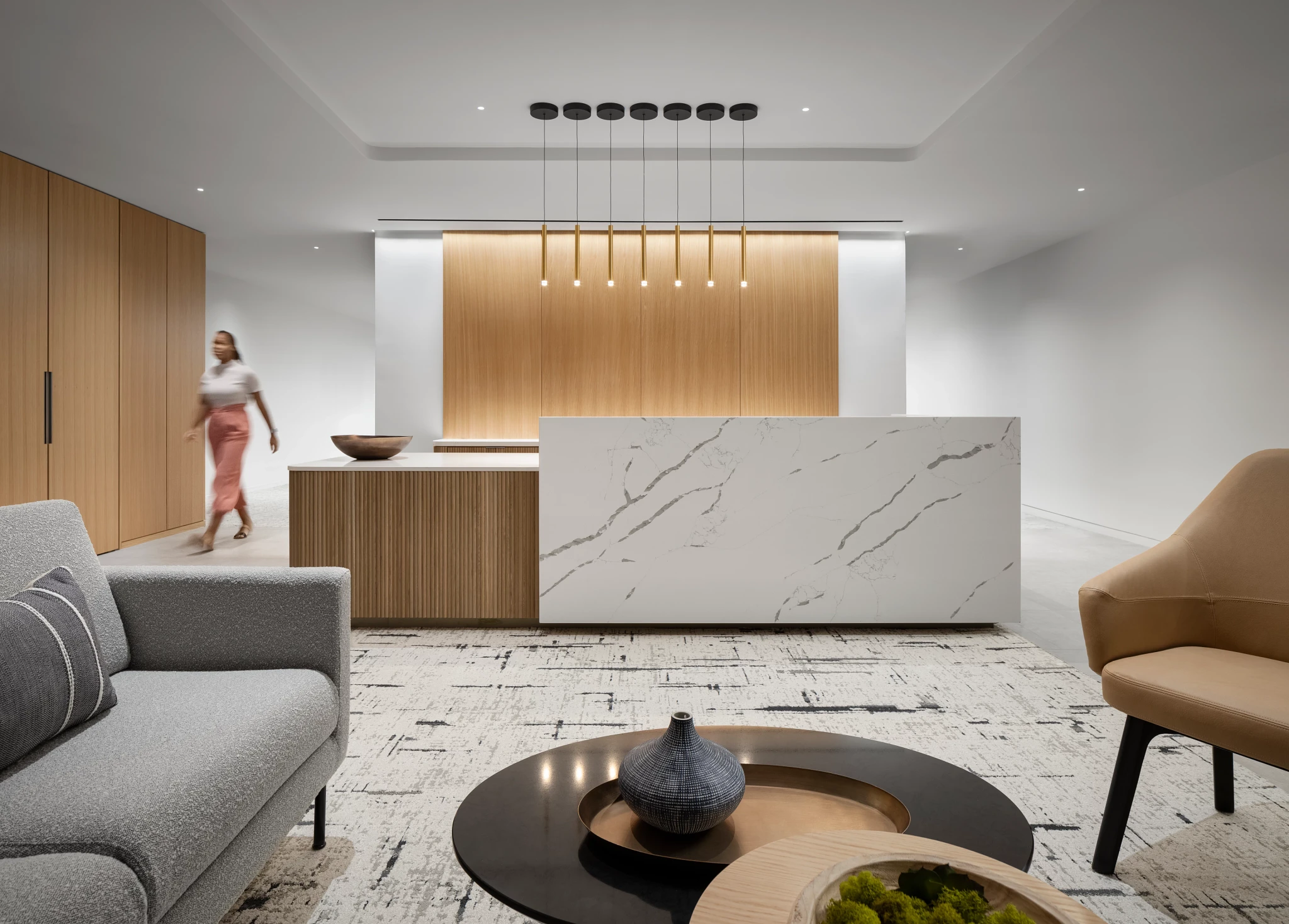 Modern workplace interior with a marble reception desk, wooden paneling, and contemporary furniture