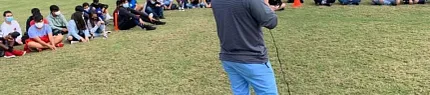Outdoor gathering on artificial turf field Group of people sitting on artificial grass field with speaker