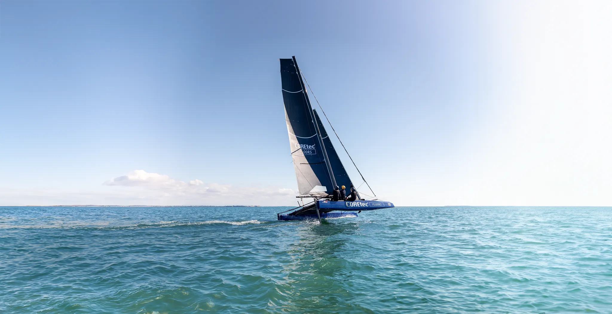 Sailing catamaran on open sea with clear blue sky