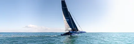 Catamaran sailing on a sunny day in open waters Sailing catamaran on open sea with clear blue sky