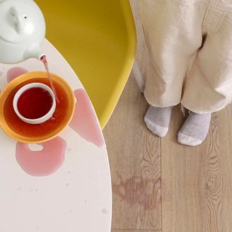 child standing beside a table where she is spilling juice onto a coretec vinyl floor