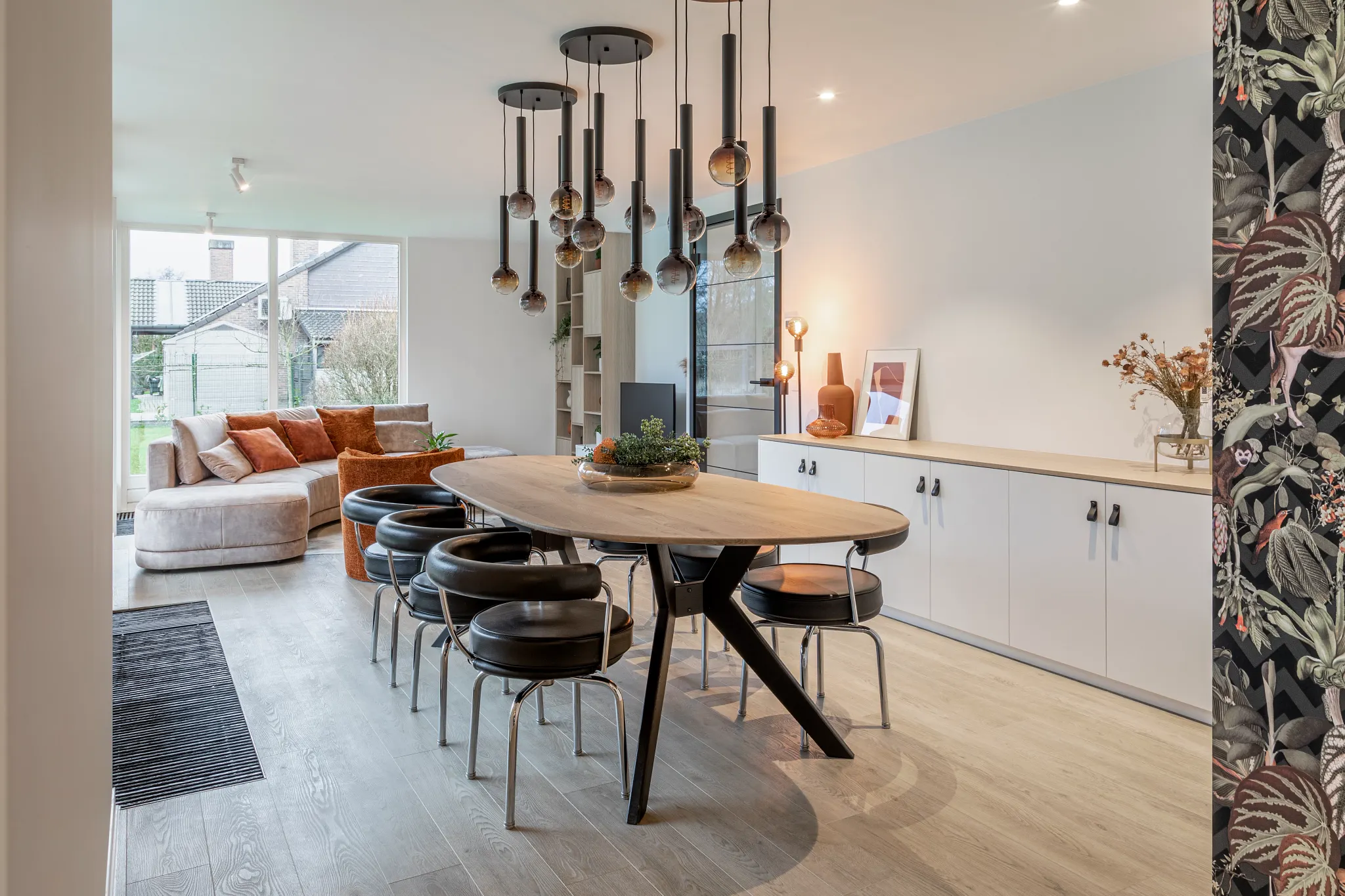 Modern dining room with wood look luxury vinyl plank flooring, featuring a round table and contemporary lighting fixtures