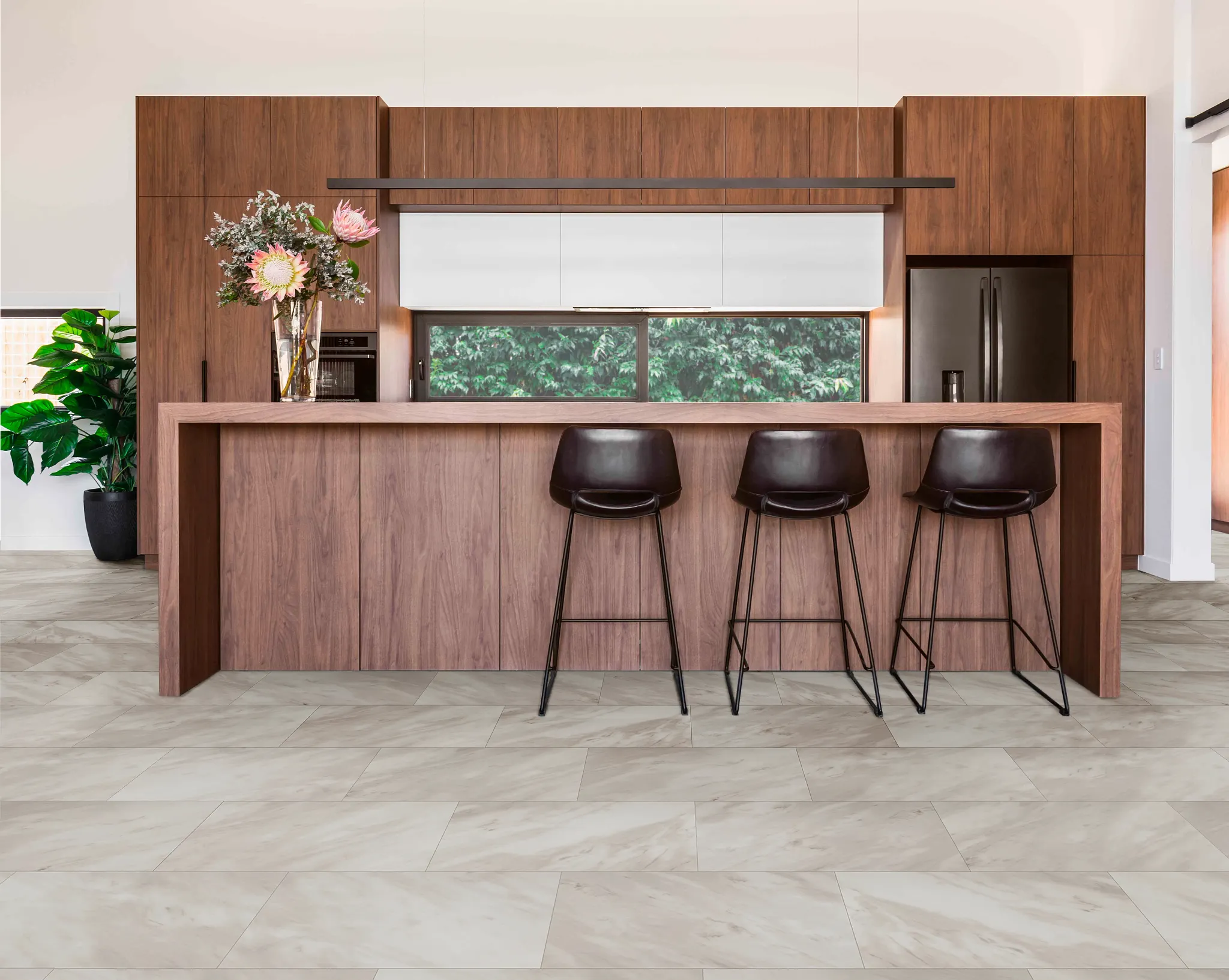 kitchen with luxury vinyl tile floor in a stone look with 2402x1201 inch tiles brown wooden cabinets and bar stools