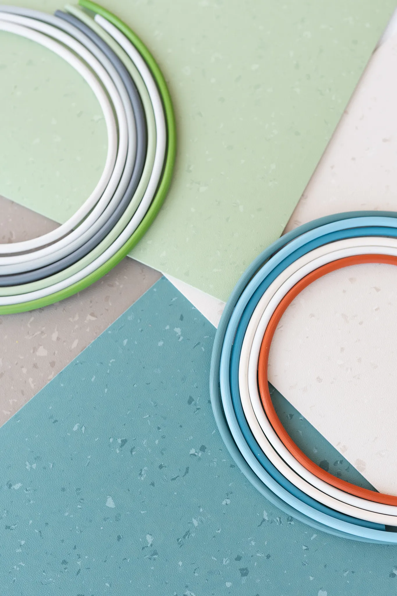 Swatch of commercial heterogeneous sheet vinyl flooring in green, blue, beige, and gray colors with circular color samples
