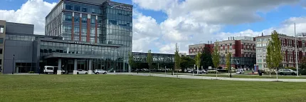Contemporary architecture with lush landscape Modern building with glass facade and green lawn under blue sky