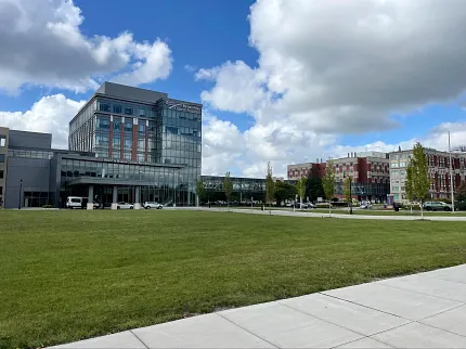 Contemporary architecture with lush landscape Modern building with glass facade and green lawn under blue sky