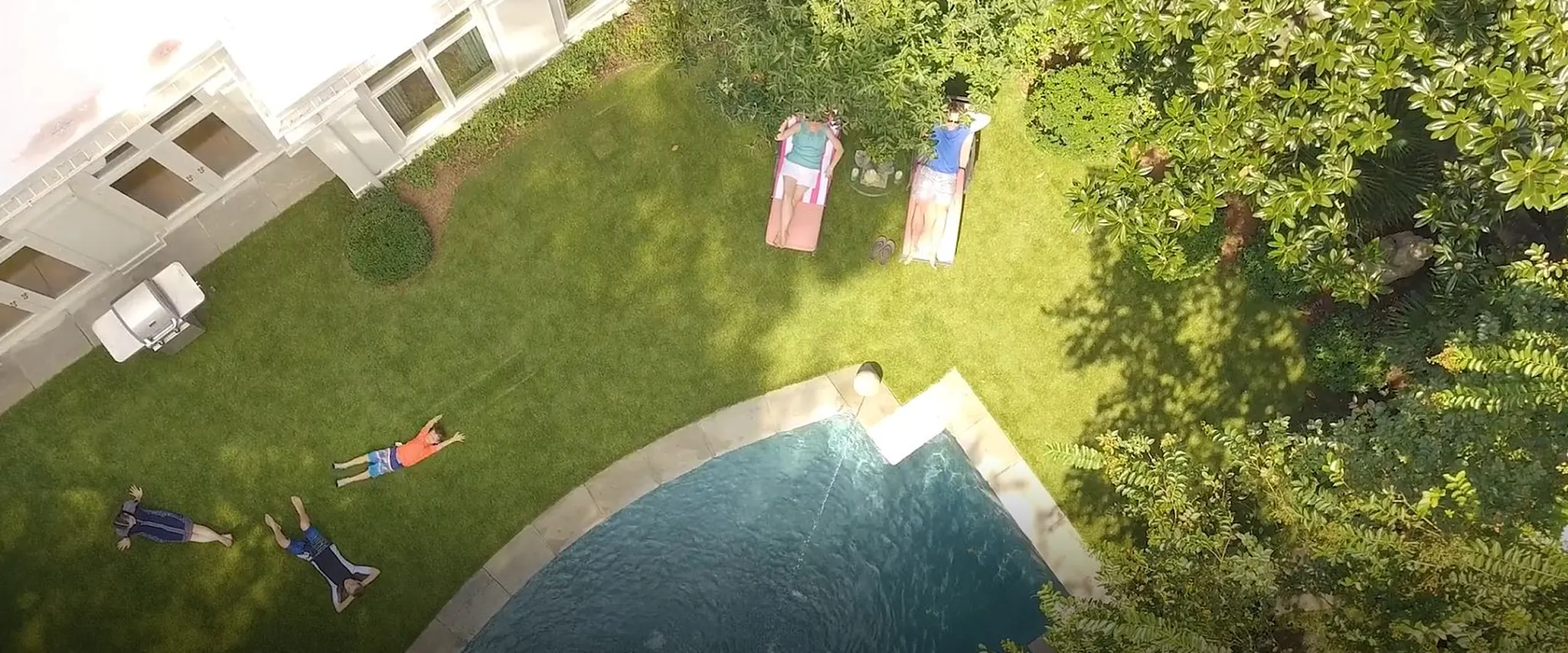 Aerial view of people relaxing by a pool in a backyard