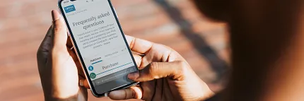 Browsing FAQs on a smartphone Person holding a smartphone displaying frequently asked questions on a website