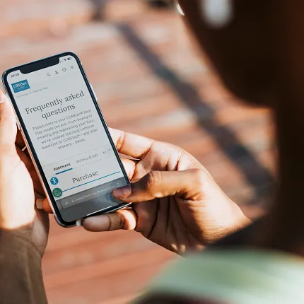 Browsing FAQs on a smartphone Person holding a smartphone displaying frequently asked questions on a website
