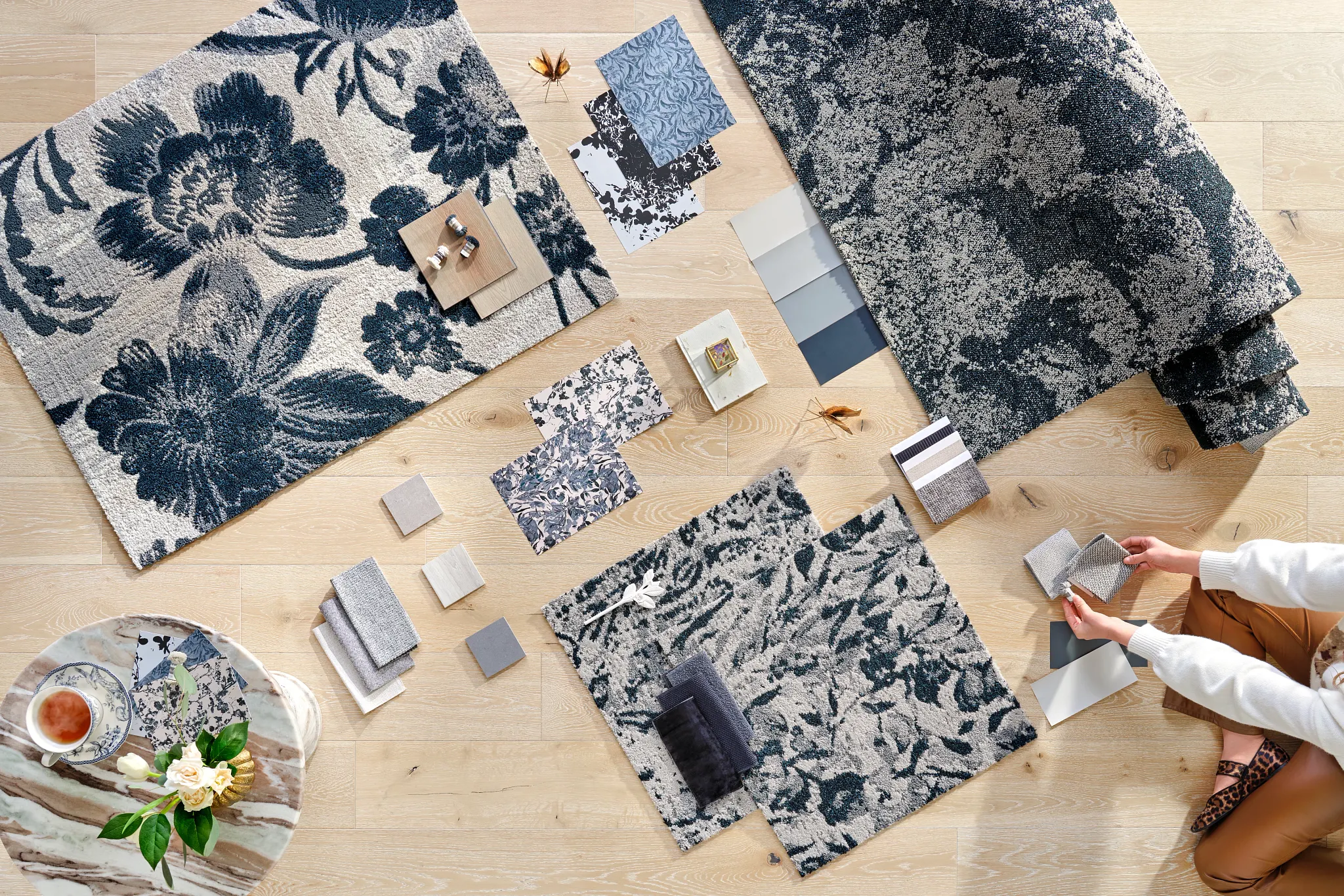 Floral carpet swatches in blue and gray tones on wooden floor