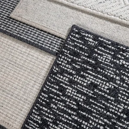 100% Wool Carpet Swatches in Black, White, and Beige Patterns Close-up of 100% wool carpet swatches in various patterns and colors including black, white, and beige