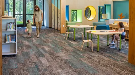 Education Facility with Commercial Carpet Tile Flooring in Gray and Teal Education facility with commercial carpet tile flooring in shades of gray and teal, featuring wooden beams and colorful children's area with tables and chairs