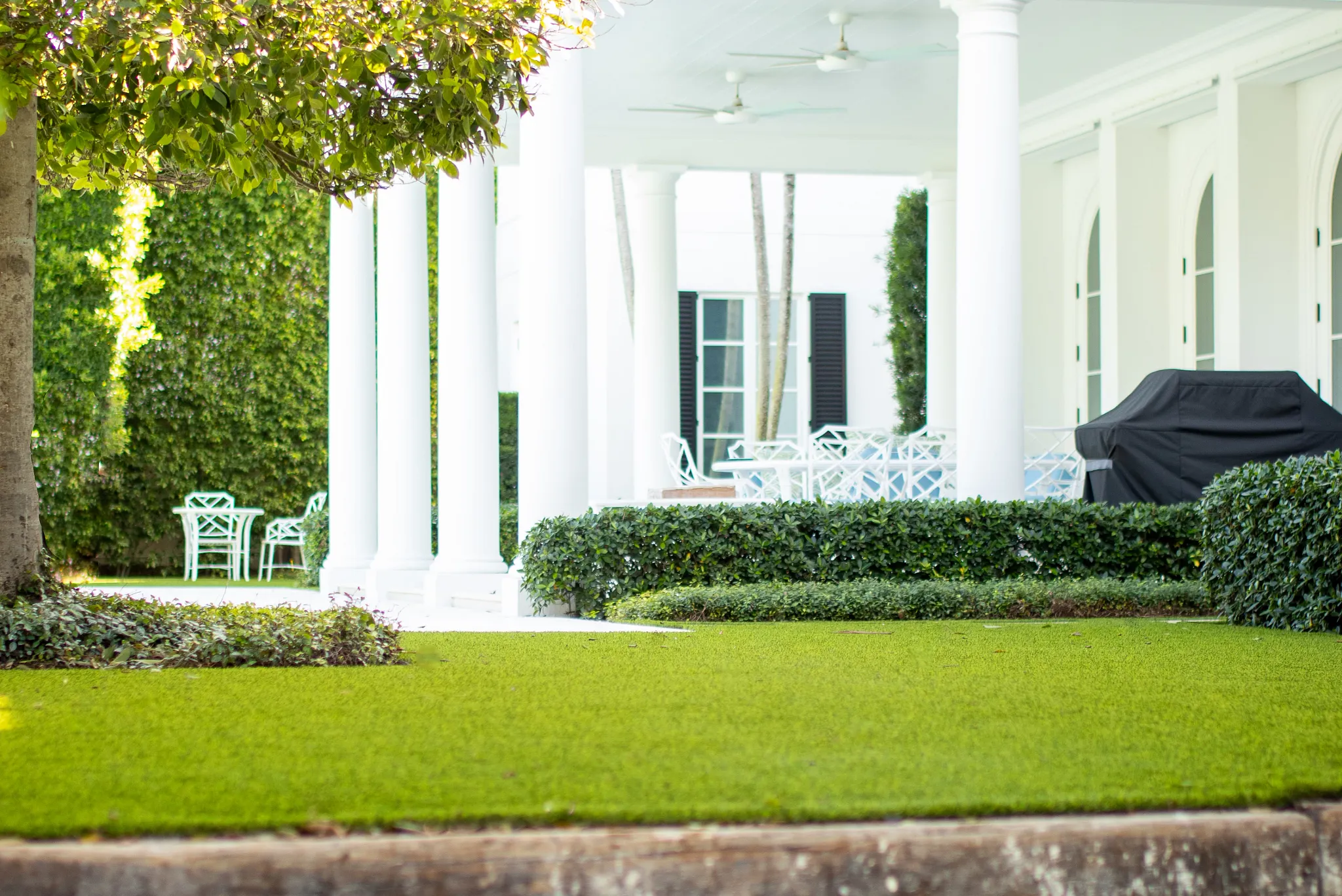 Elegant outdoor patio with white columns and green lawn