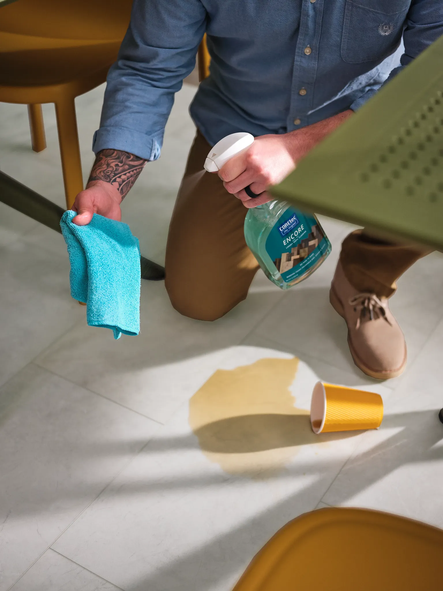 Man cleaning spill on Coretec Residential SPC vinyl flooring with cleaning spray and cloth