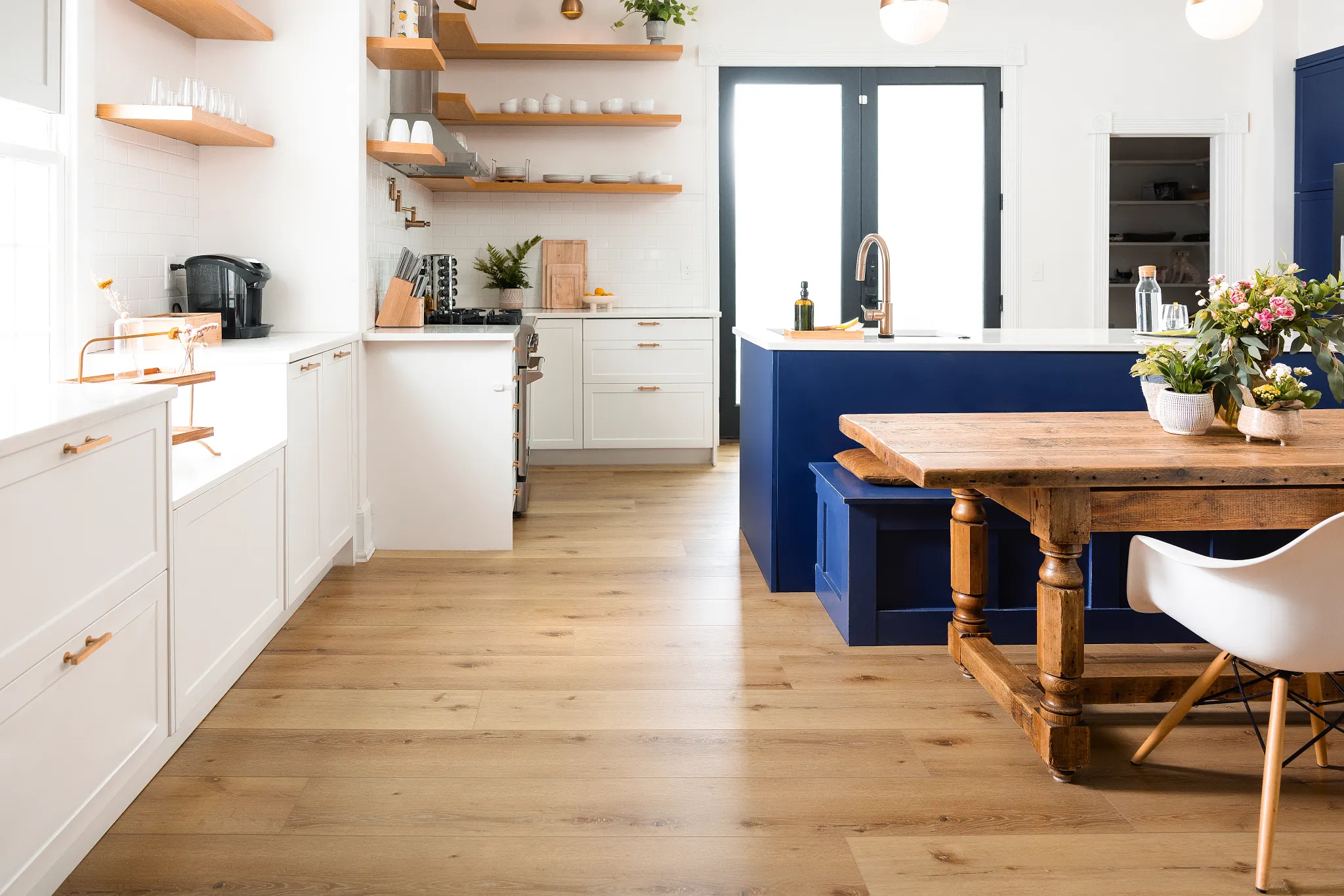Modern kitchen with light wood flooring, white cabinets, and blue island