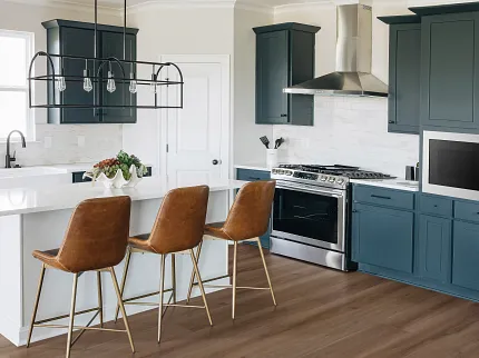 Stylish kitchen with durable hardwood flooring and contemporary design elements Modern kitchen with brown hardwood flooring, navy cabinets, and brown leather bar stools