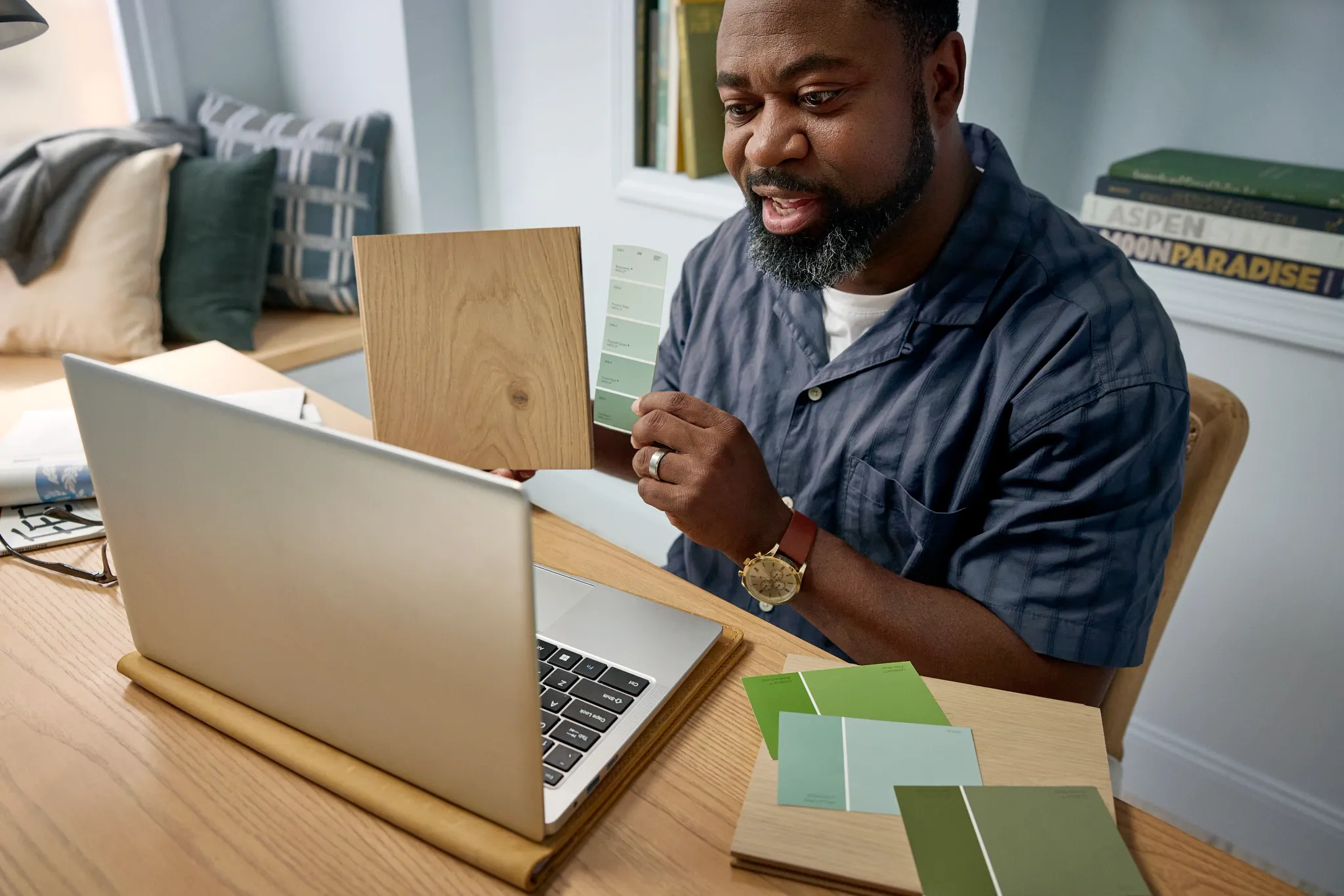 Overhead view of two people selecting flooring samples including carpet, hardwood, and tile on a black table