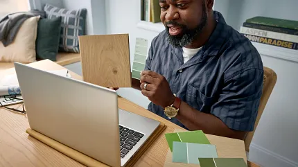 Flooring selection process with carpet, hardwood, and tile samples for a comfortable home ambiance Overhead view of two people selecting flooring samples including carpet, hardwood, and tile on a black table