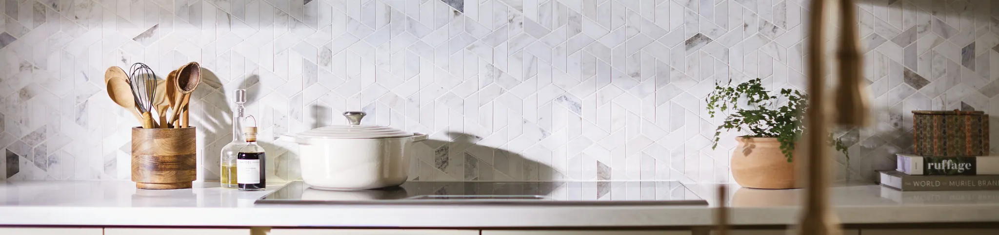 Modern kitchen with geometric patterned tile backspash in neutral tones, featuring a sleek black range hood and white cabinetry