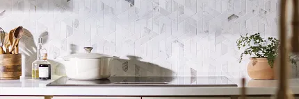 Geometric Patterned Tile Backsplash in Contemporary Kitchen Design Modern kitchen with geometric patterned tile backspash in neutral tones, featuring a sleek black range hood and white cabinetry