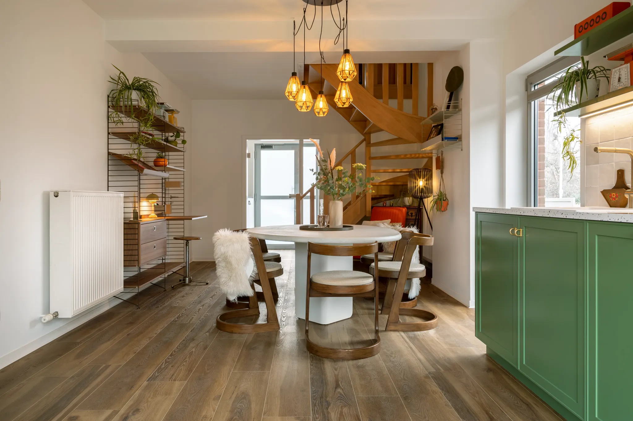 dining room with wood look luxury vinyl plank floor with a round table and chairs green cabinetry and a spiral staircase