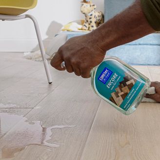 A man using Encore cleaner to clean a spill off of the floor.