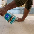 Easy to clean wood look luxury vinyl flooring in a modern living room scene Man cleaning light wood look vinyl flooring with cleaning solution in a modern living room