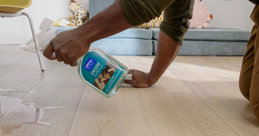 Easy to clean wood look luxury vinyl flooring in a modern living room scene Man cleaning light wood look vinyl flooring with cleaning solution in a modern living room