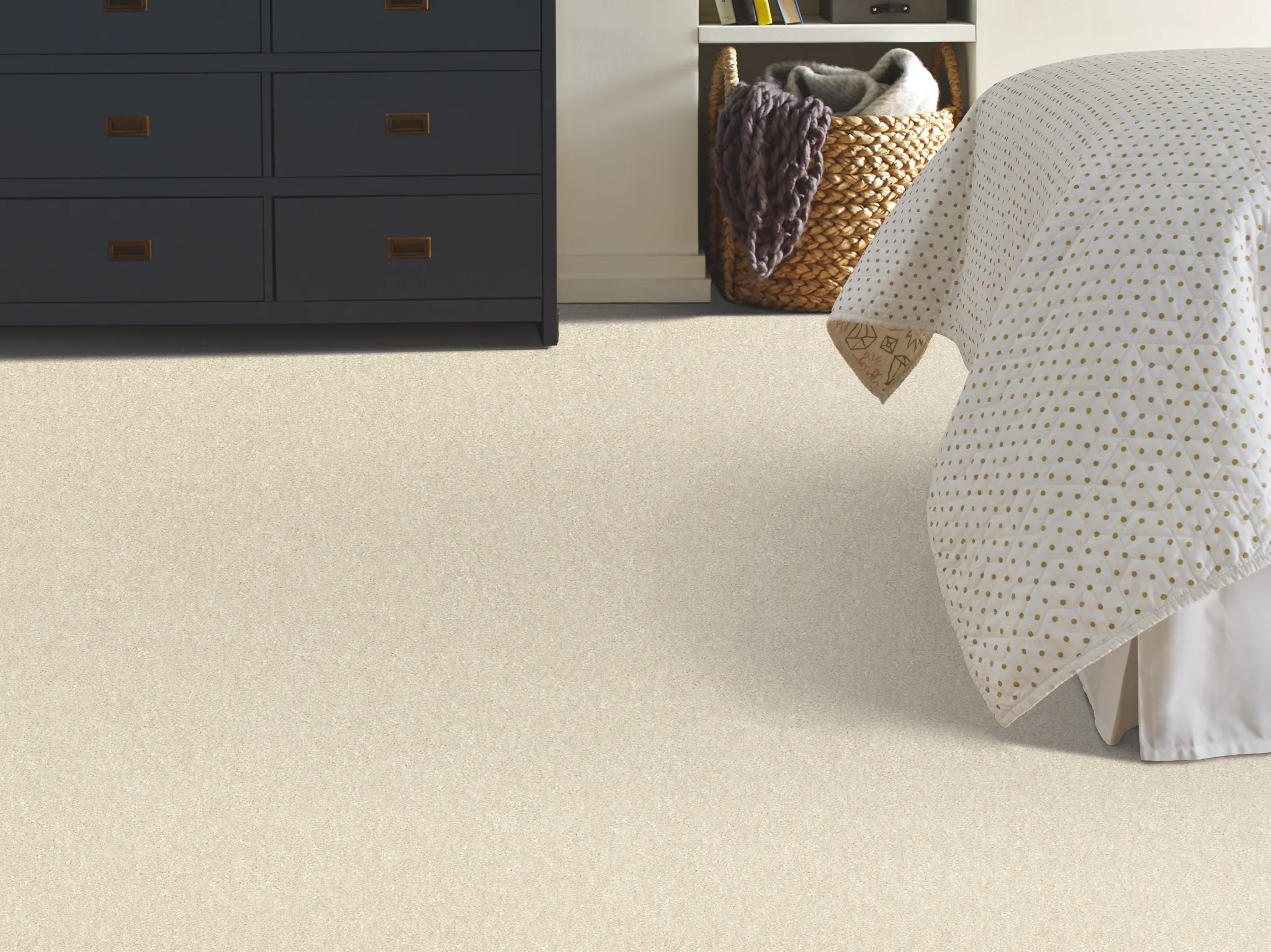 Cozy bedroom with beige carpet flooring, dark blue dresser, and polka dot bedding for a comfortable home feel