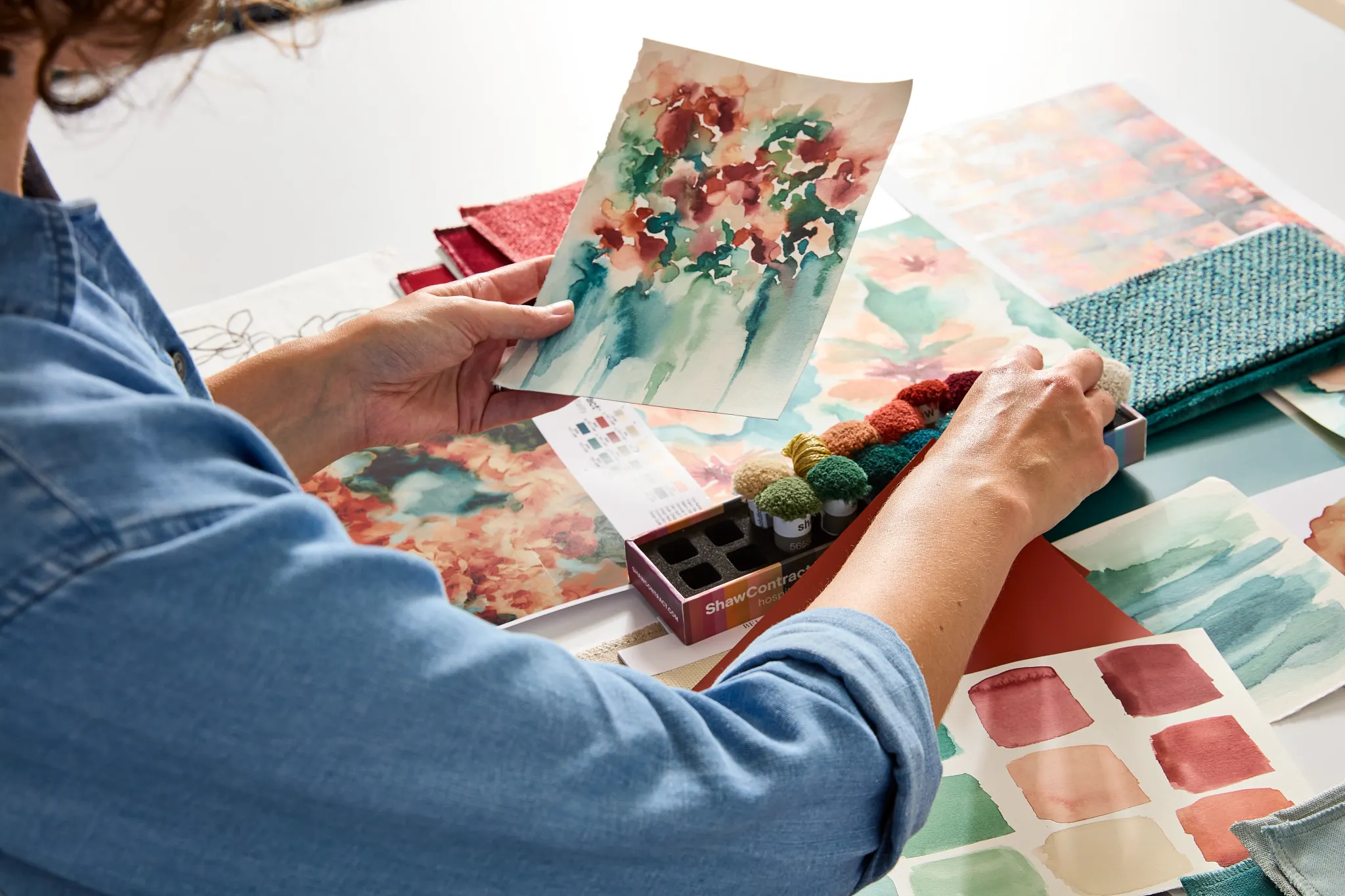 Designer reviewing colorful fabric swatches and watercolor designs for flooring inspiration