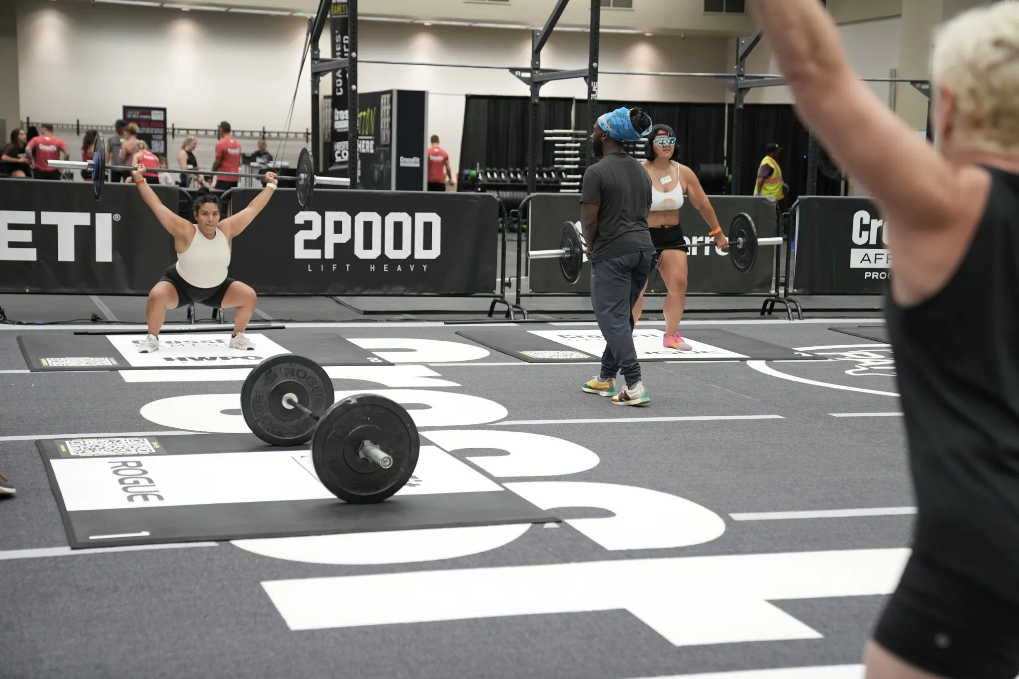 Indoor gym scene with athletes lifting weights on branded flooring