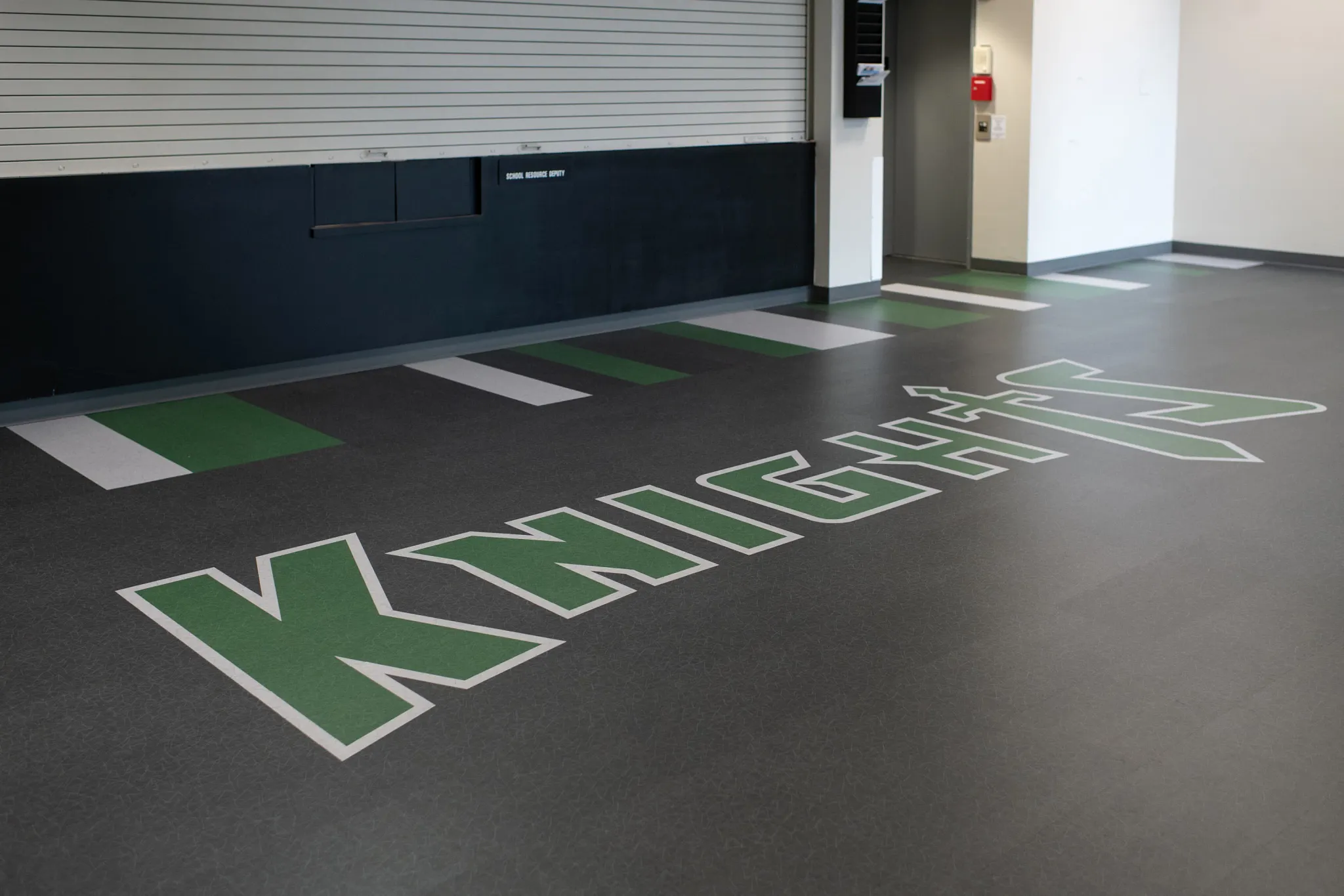 Heavy commercial luxury vinyl tile flooring with "KNIGHTS" logo in green and white