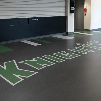 Durable LVT flooring for educational facilities Heavy commercial luxury vinyl tile flooring with "KNIGHTS" logo in green and white