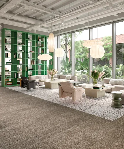 Contemporary office space with beige carpet tile and green accents Modern workplace lounge with beige commercial carpet tile flooring, green bookshelf, and large windows